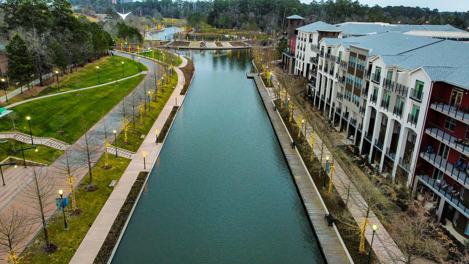 Mixed-use buildings along a waterway, representative of The Woodlands